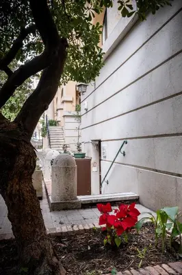 a tree sitting next to a building with red flowers at Vatican36 Guest House in Rome