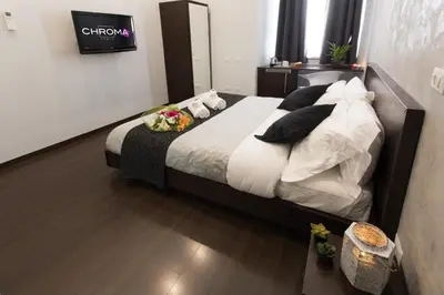 a bedroom with a bed with white sheets and black pillows at Chroma Italy - Chroma Pente in Rome