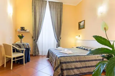 a hotel room with a bed and a chair and a window at Vatican Town in Rome