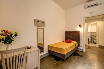 a small bedroom with a bed and a mirror at Feronia Guest house in Rome