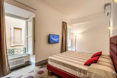 a bedroom with a bed with red pillows and a window at Feronia Guest house in Rome