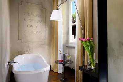 a bathroom with a white toilet and a table with flowers at Relais Orso in Rome