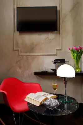 a red chair and a table with a book and a wine glass at Relais Orso in Rome
