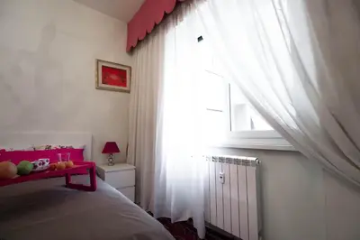 a bedroom with a bed and a window with white curtains at Asher's House Colosseum in Rome