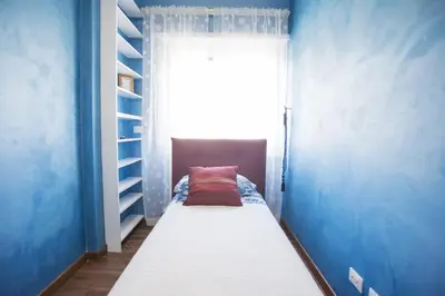a bed in a blue room with a window at Stradivari Luxury Apartment in Rome