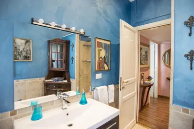 a blue bathroom with a sink and a mirror at Stradivari Luxury Apartment in Rome