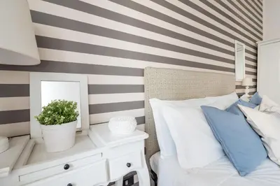 a bedroom with a striped wall with a bed and a mirror at Suite 06 in Rome