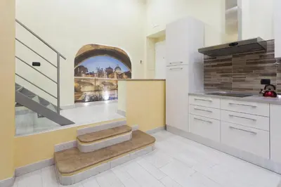 a kitchen with white cabinets and a staircase in it at Trastevere Charming Loft in Rome