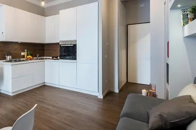 a kitchen with white cabinets and a living room at Z-ArchSuites in Rome