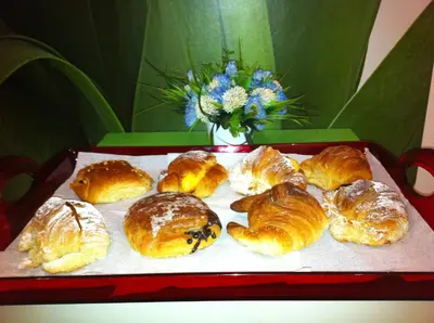 a tray of pastries on a table with a vase of flowers at Rhome86 in Rome