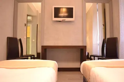 a room with two beds and a tv on the wall at Tiburtina House in Rome