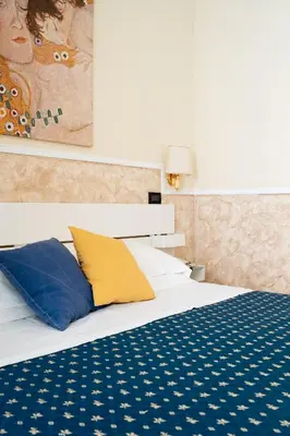 a bed with blue and yellow pillows and a painting at Hotel Ascot in Rome