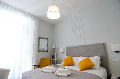 a white bedroom with a large bed with yellow pillows at Eighty Four Rooms in Rome