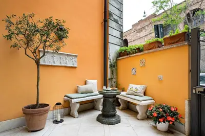 a courtyard with a tree and benches on a building at Domus Pinciana in Rome