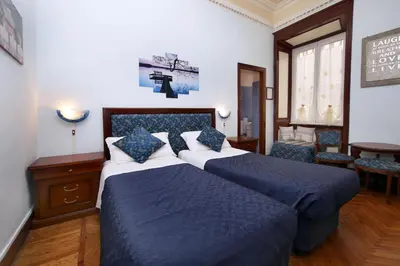 a bedroom with two beds and a cross on the wall at Tibullo Guesthouse in Rome