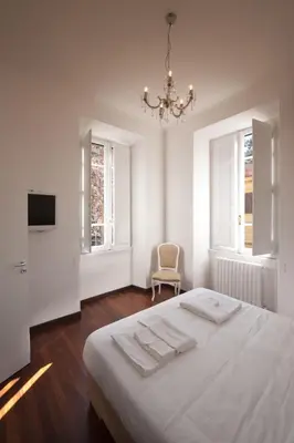 a white bedroom with a bed and a chandelier at Imperia Suite in Rome