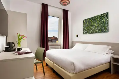 a hotel room with a bed and a desk and a window at Colosseo Panorama by GHOR in Rome