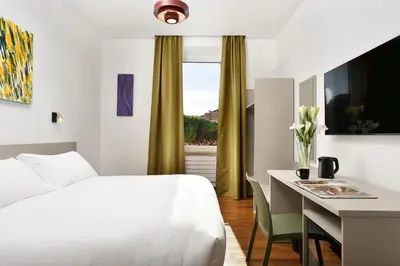 a hotel room with a bed and a desk and a bed and a window at Colosseo Panorama by GHOR in Rome
