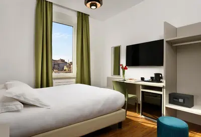 a hotel room with a bed and a desk and a window at Colosseo Panorama by GHOR in Rome