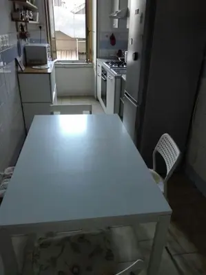 a kitchen with a white table and a refrigerator at Liudan&rooms Affittacamere in Rome