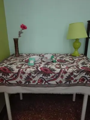 a bed with a flowered bedspread and a vase with a flower at Liudan&rooms Affittacamere in Rome