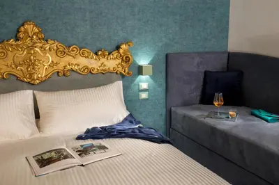 a bedroom with a bed with a gold headboard and a glass of wine at GCF Luxury Suites, Guest house in Rome