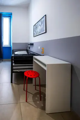 a room with a desk with a stool and a bed at Melting Pot Rome in Rome