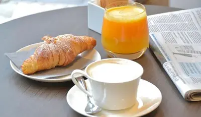 a table with a cup of coffee and a croissant and orange juice at MILLINA SUITES IN NAVONA in Rome