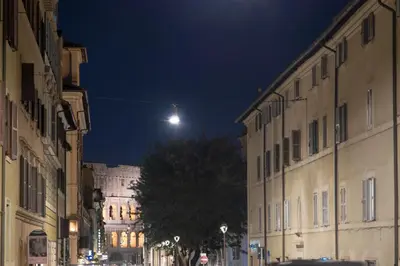 a city street at night with a moon in the sky at The Dream Of Colosseum in Rome