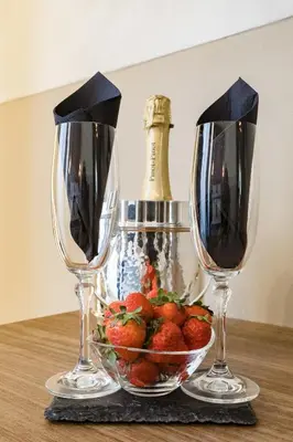 two wine glasses and a bowl of strawberries on a table at A World Aparts - Barberini Boutique Hotel in Rome