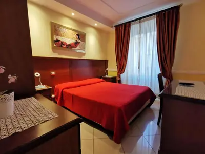 a hotel room with a red bed and a window at Hotel Valentino Palace in Rome