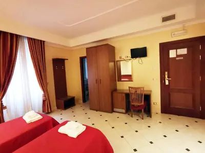 a hotel room with two beds and a desk at Hotel Valentino Palace in Rome
