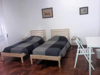 two beds in a room with a table and a chair at A casa di Robi in Rome