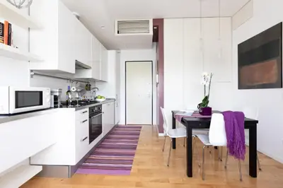 a kitchen with white cabinets and a black table with a purple rug at Lambertone, cozy flat in Rome, Aurelio Vatican in Rome