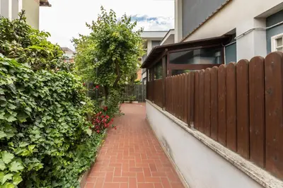a brick sidewalk next to a fence with flowers at Lambertone, cozy flat in Rome, Aurelio Vatican in Rome