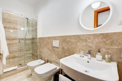 a bathroom with a sink and a toilet and a mirror at Lovely and modern nest near the Colosseum in Rome
