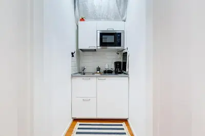 a small kitchen with white cabinets and a microwave at Lovely and modern nest near the Colosseum in Rome