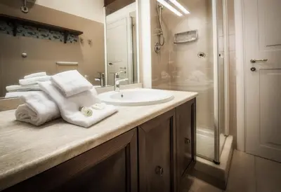 a bathroom with a sink and a shower with towels at Rome As You Feel - Baccina 95 Forum Apartment in Rome