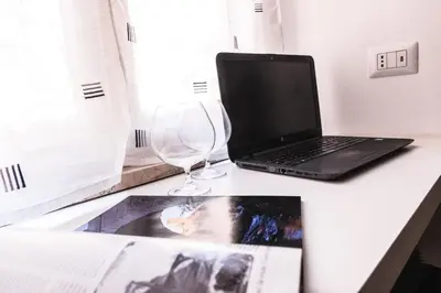a laptop computer sitting on a desk next to a wine glass at Roma Centrale Fidelis in Rome