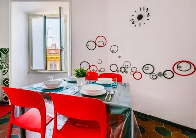 a dining room table with red chairs and a clock on the wall at Lele Rooms San Lorenzo in Rome