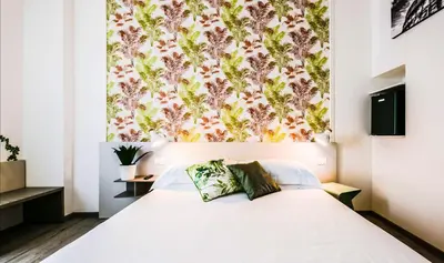 a bedroom with a white bed with a floral wallpaper at Lele Rooms San Lorenzo in Rome