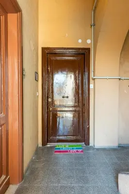 a wooden door in a hallway with a colorful mat in front of it at Lele Rooms San Lorenzo in Rome