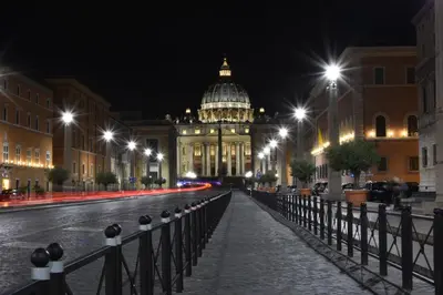 a city street at night with a building with a dome at Virgilio Suite in Rome