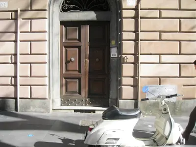 a scooter parked in front of a building with a door at Merulana Suite in Rome