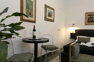 a room with a table with a bottle of wine and a chair at Houspitality Caesar Bed & Breakfast in Rome