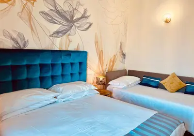 a bedroom with two beds and a blue headboard at Bon Ton Design Rooms by DOT Suites in Rome