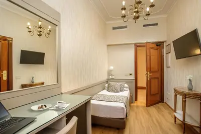 a hotel room with a bed and a desk with a laptop at Hotel Della Torre Argentina in Rome
