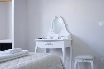 a white dressing table with a mirror next to a bed at Clara Domus in Rome