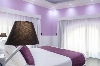 a purple bedroom with a bed and a lamp at THE ONE Boutique Hotel & SPA Roma in Rome