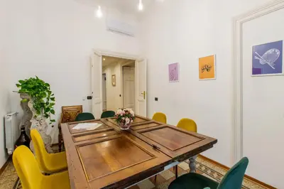 a dining room with a wooden table and yellow chairs at Home Of Arts in the Center in Rome